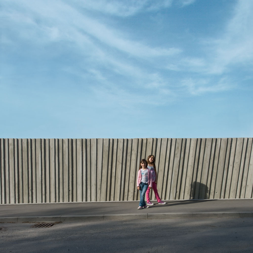 Zur Straße zeigt sich das Gebäude mit einer fensterlosen Betonwand