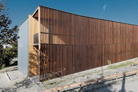 Hinter der holzverkleideten Nordfassade befindet sich ein Laubengang, der die Hotelzimmer erschließt