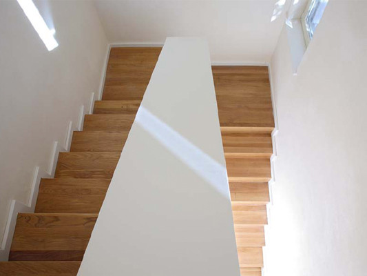 Holztreppe ins OG, an den Wänden weißen Lehmfeinputz
