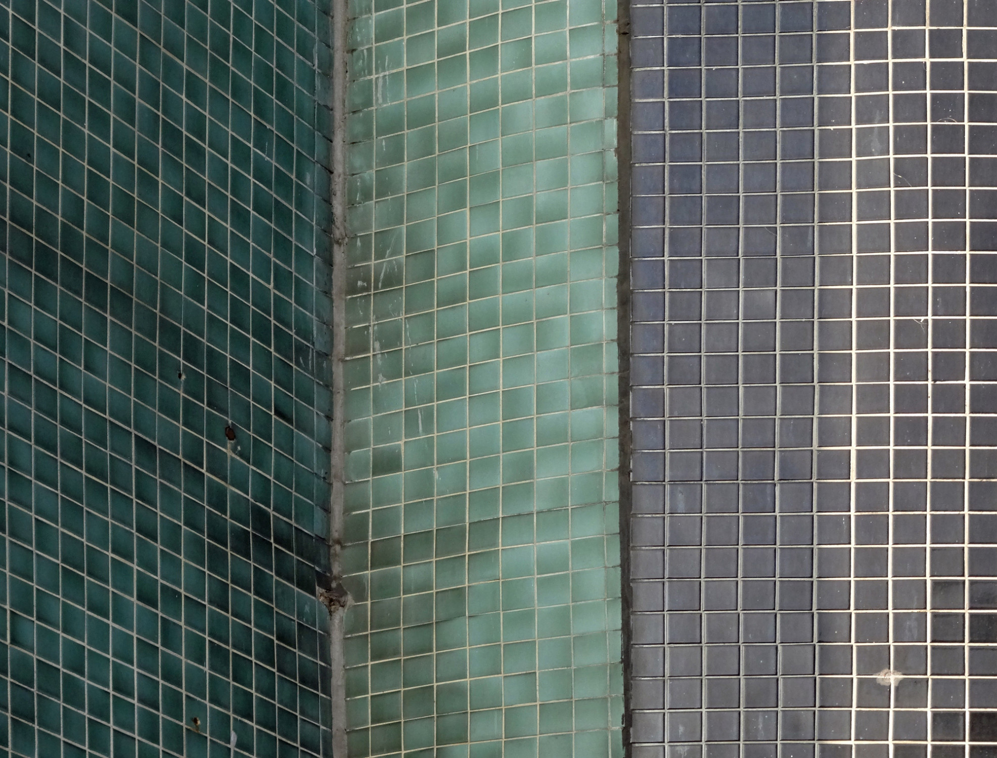 Dunkle Verfärbungen an den grünen Mosaikfliesen einer Berliner Hausfassade
