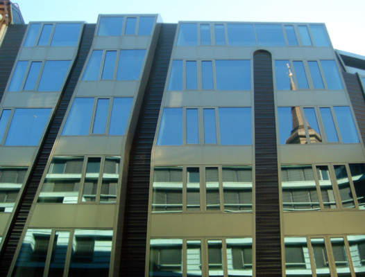 In den Glasflächen der Fassade spiegeln sich die gegenüberliegende Bebauung und der Kirchturm Sankt Katharinen