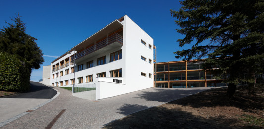 Der dreigeschossige, zweiflügelige Neubau ist weiß verputzt