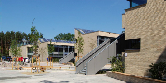 Hinter den Gebäudeflügeln ergänzt eine Sporthalle die Grundschule