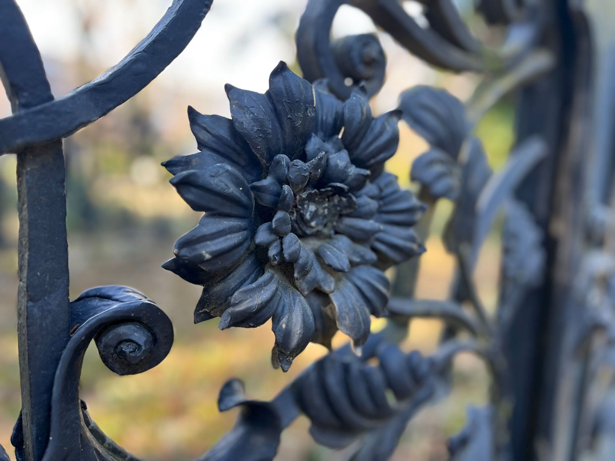 Schmiedeeisen findet vor allem in der Herstellung von Toren, Portalen und Zäunen Anwendung. Im Bild: Kunstvoll gearbeitete Chrysanthemenblüte an einem historischen Gittergrab des Alten Friedhofs St. Jacobi in Berlin Neukölln