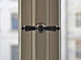 Die Fensterolive ist ein klassischer Drehgriff zur Betätigung von Fenstern und Fenstertüren. Im Bild: Fensterolive aus Messing ca. 1905