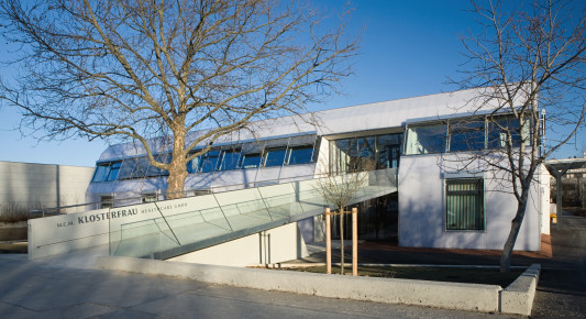 Nach dem Umbau: Eine lange Betonrampe dient zur Erschließung, die Fassade sind mit weißen Polycarbonatplatten gestaltet