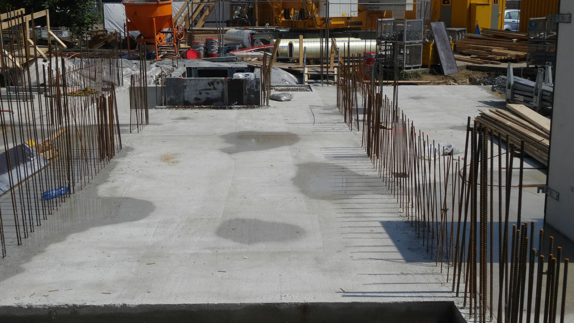Betonierte Gründung mit Anschlussbewehrung: Die herausragenden Stäbe markieren die späteren Wandachsen und leiten Kräfte zwischen Fundament und aufgehenden Bauteilen weiter.