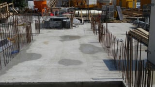 Betonierte Gründung mit Anschlussbewehrung: Die herausragenden Stäbe markieren die späteren Wandachsen und leiten Kräfte zwischen Fundament und aufgehenden Bauteilen weiter.