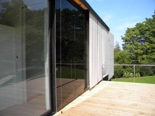 Im Bereich der Zwischenräume ist die Südfassade bedeckt von schwarzen, rahmenlosen Kassettenmodulen mit Dünnschichtzellen, deren Optik dunklem Glas ähnelt