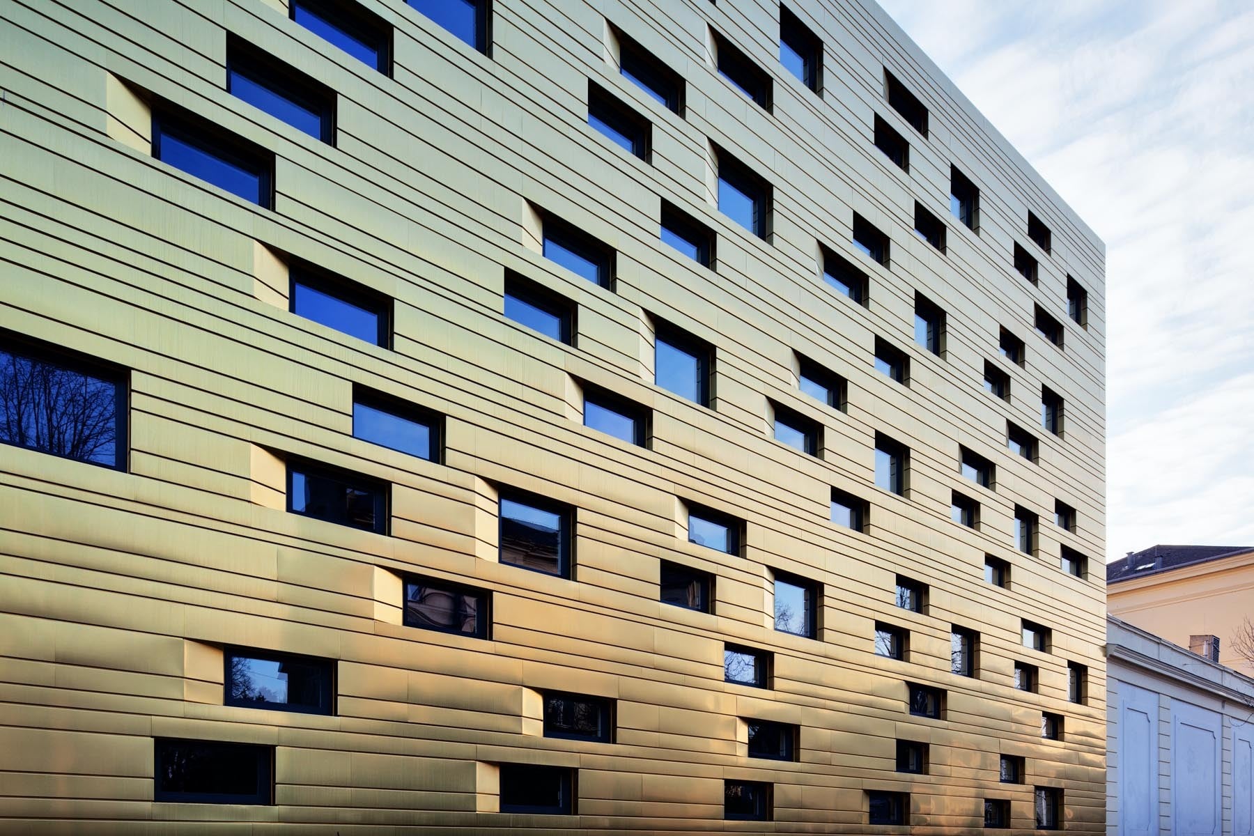 Zwei verschieden formatige Fenstertypen sind unregelmäßig in der Fassade angeordnet