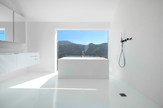 Eine freistehende Badewanne steht im Zentrum des Bades, platziert vor einem großen, quadratischen Fenster mit Blick in die Hollywood Hills