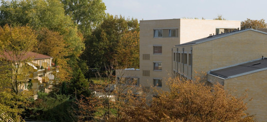 Die einheitliche Fassadengestaltung mit einer weißlich-gelben Klinkerfassade verbindet Alt- und Neubauten