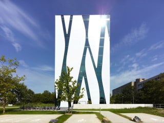Bibliotheksgebäude mit einer Fassade aus weißem Glasmosaik, auf der sich Fensterbänder gleich Flüssen hinabschlängeln