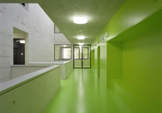 Als Materialien kommen Sichtbeton mit feiner Holzstruktur, lackierte Akustikverkleidungen sowie Böden aus Kautschuk zum Einsatz