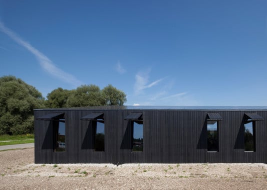 Schwarze Holzleisten und schmale Fenster mit Klappläden an der Südfassade