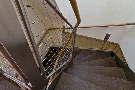 Moderne Materialien wie Stahlprofile und -gewebe im alten Treppenhaus