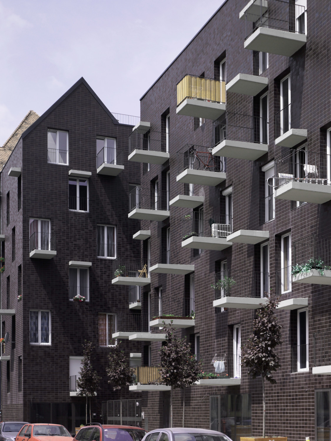 Verschieden tiefe Auskragungen in Form sehr heller Sichtbetonplatten durchbrechen die Fassade