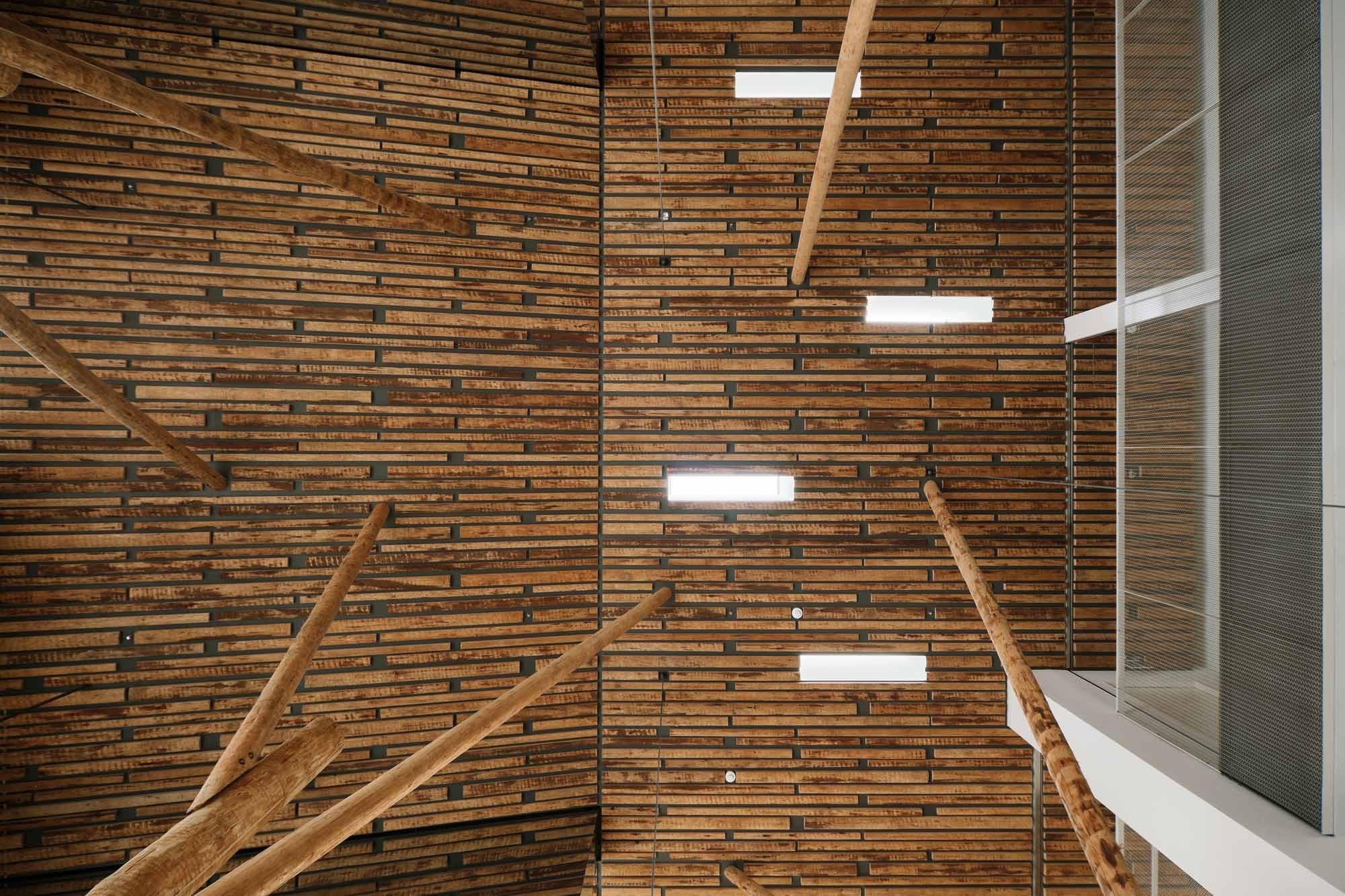 Durch kleine Öffnungen fällt Licht in das dreigeschossige Atrium