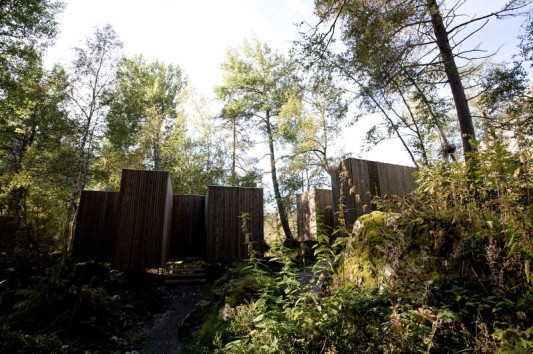 Die Holzbauten stehen auf Stützen und sind individuell an die Topografie angepasst