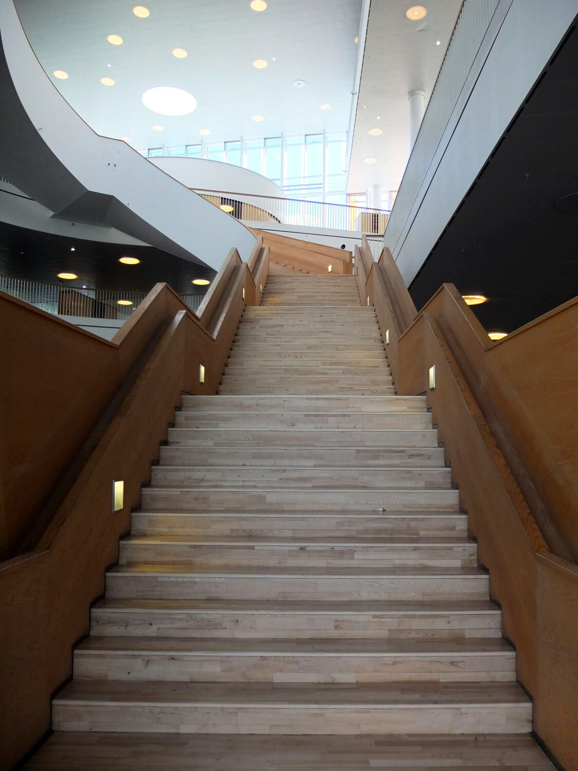 Dreiläufige gerade Holztreppe im Ørestad-Gymnasium in Oslo.