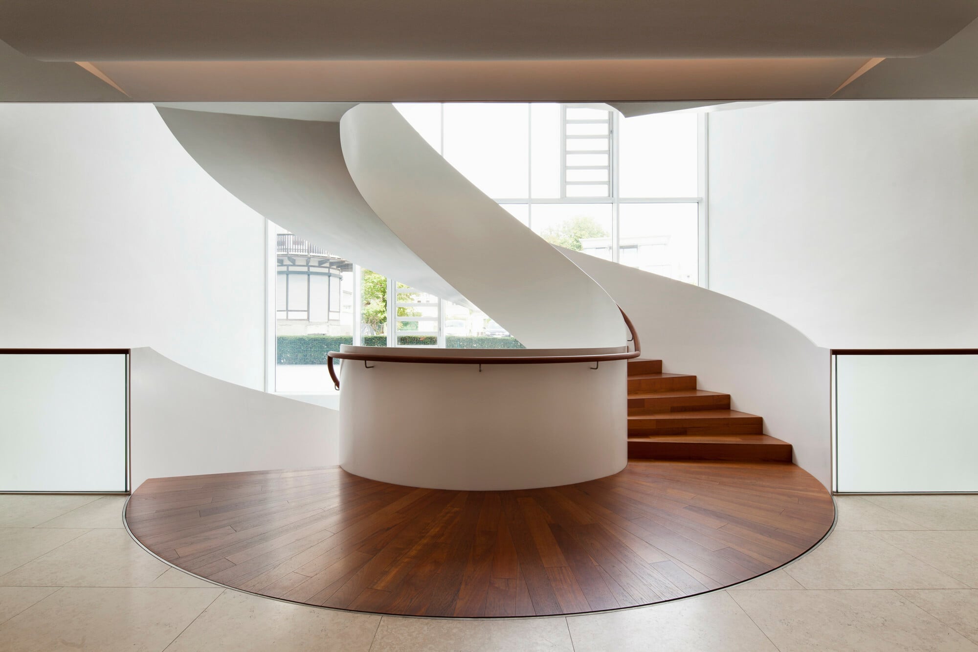 Ellipsenförmig gebogene Wendeltreppe mit weiß lackierten Flachstahl-Brüstungswangen im Seehotel Riva in Konstanz