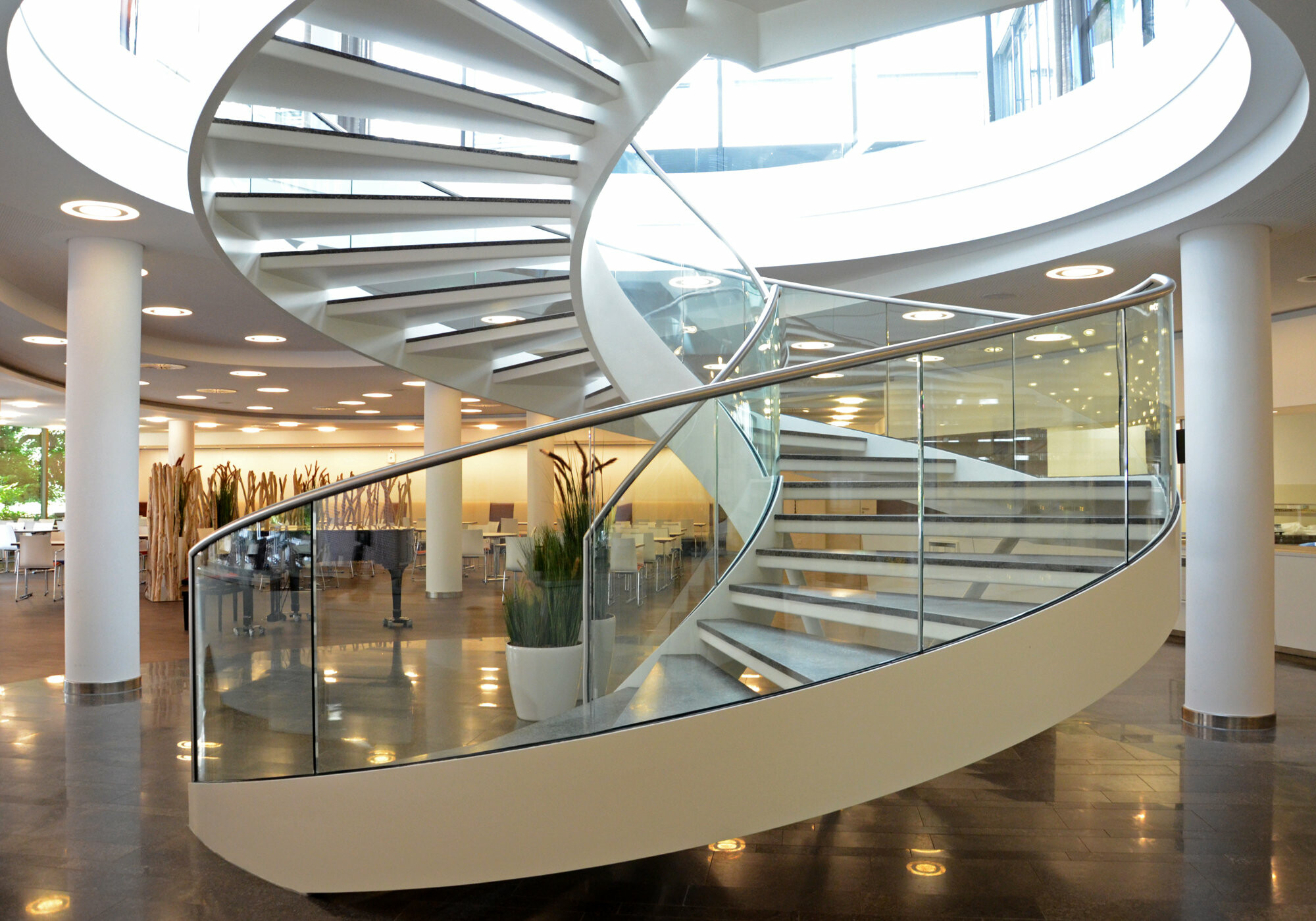 Wendeltreppe mit gebogenem Glasgeländer im Foyer der Inter Krankenversicherung in Mannheim