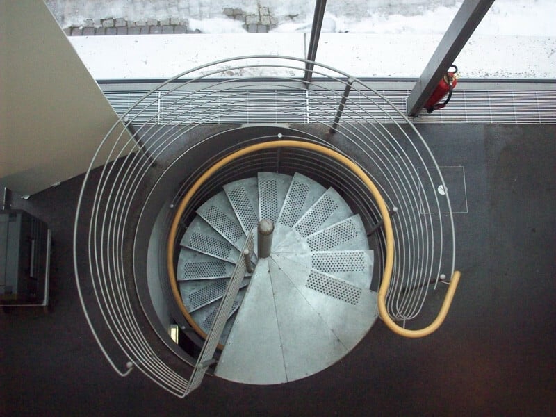 Spindeltreppe aus Stahl mit über das Podest an der Austrittsebene befestigter Spindel