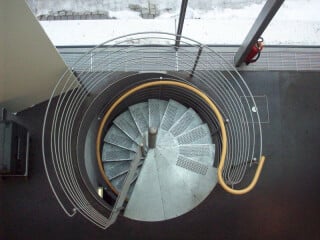 Spindeltreppe aus Stahl mit über das Podest an der Austrittsebene befestigter Spindel