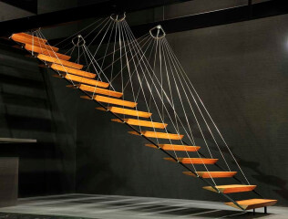 Beispiel einer abgehängten Treppe mit fächerartig angeordneten Zugstäben aus Stahl. Die Treppe der Firma Zeitform wurde in Anlehnung an das statische Prinzip von Hängebrücken entwickelt.