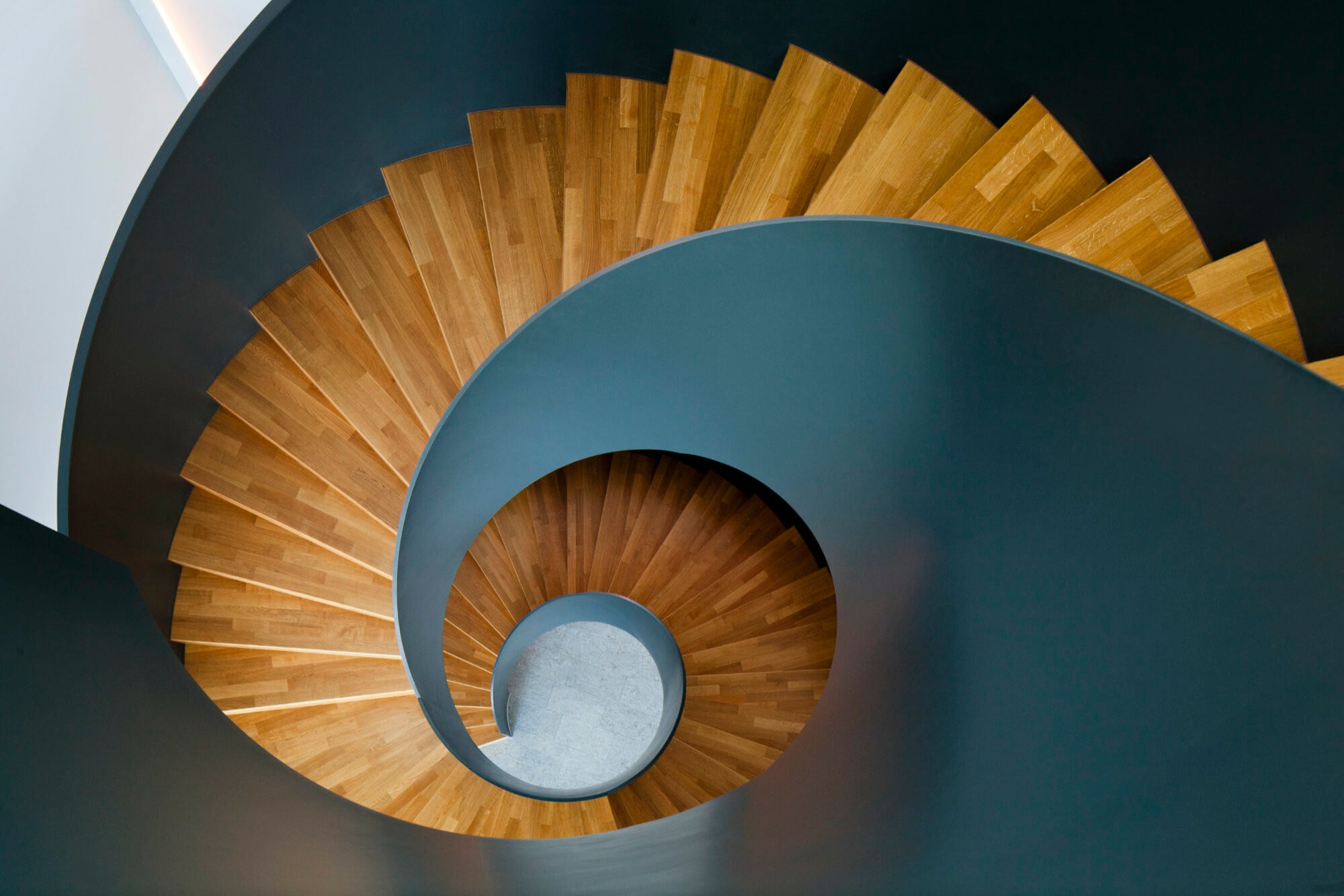 Bei der gleichmäßig gerundeten Wendeltreppe für Berger-Lacke treffen warme Holztöne auf markantes Grau der Stahlteile.