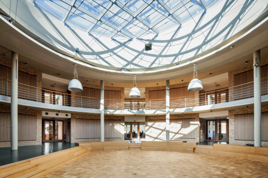 Im Zentrum des Gebäudes dient ein kreisrundes Atrium als Ort der Begegnung und Kommunikation