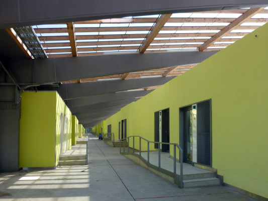 Gläserne Halle mit eingestellten, leuchtend grünen Baukörpern