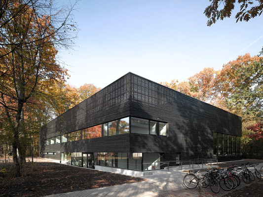 Mit ihrer dunklen Holzfassade fügt sich die Sporthalle in das durch den Wald geprägte Landschaftsbild