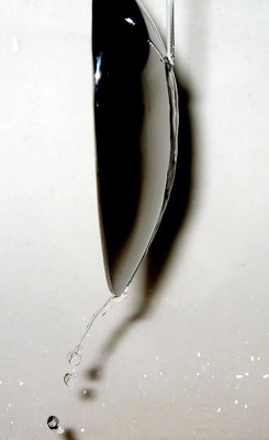 Coanda-Effekt: Das herabfallende Wasser haftet an der Oberfläche des Löffels und folgt seiner Spur, seine ursprüngliche Fallrichtung ändert sich