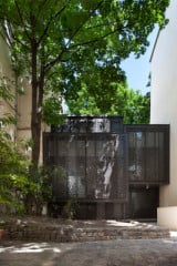 Die Südfassade des Maison Escalier wird von bronzefarbenen Faltschiebeläden aus perforiertem Aluminium verschattet