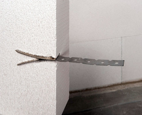 Für Porenbetonwände eignen sich Anker aus einem flachen Stahldübel mit zwei aufeinander liegenden Laschen, die sich beim Eindringen in die Wand aufspreizen, sowie einer daran befestigten Ankerlasche
