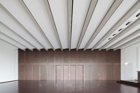Die Wand zwischen Hörsaal und Foyer ist mit einer Oberfläche aus Räuchereichenfurnier versehen und weist das gleiche Fugenbild auf wie die Außenfassade