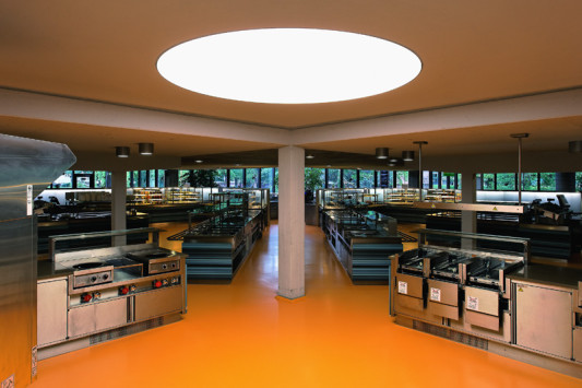Die Böden im Küchentrakt sind orange gestaltet, das Inventar besteht aus Edelstahl