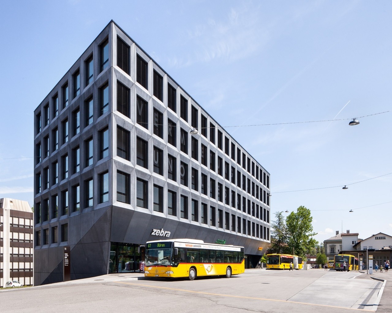Ein strenges Fassadenraster aus Sichtbetonfertigteilen umschließt das gesamte Gebäude, hier die Westfassade zum Bahnhofplatz hin