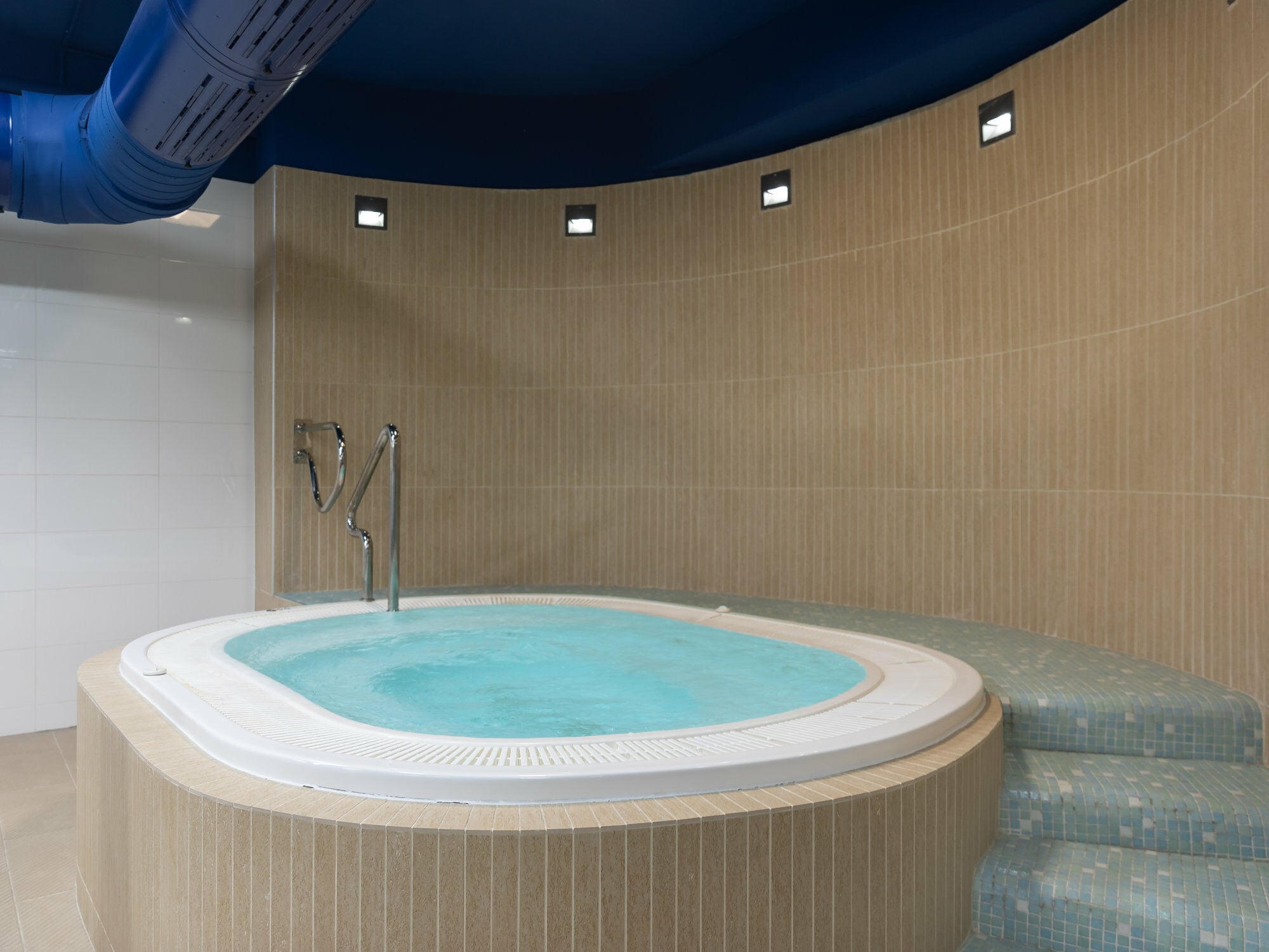 Festinstalliert: Whirlpool in einem gefliesten Podest mit integrierten Treppen