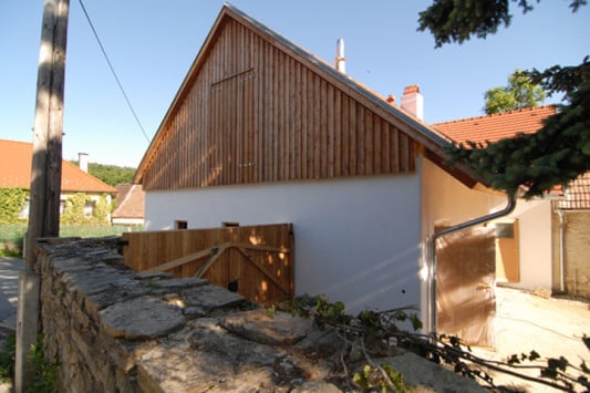 Von der Straße führt ein Holztor in den Innenhof. Der Eingang zum Wohnhaus liegt auf der Westseite des Gebäudes