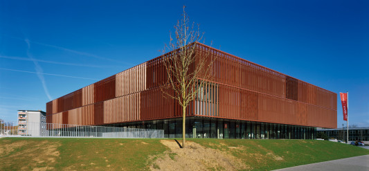 Die rostrote Lamellen-Fassade umschließt beide Obergeschosse