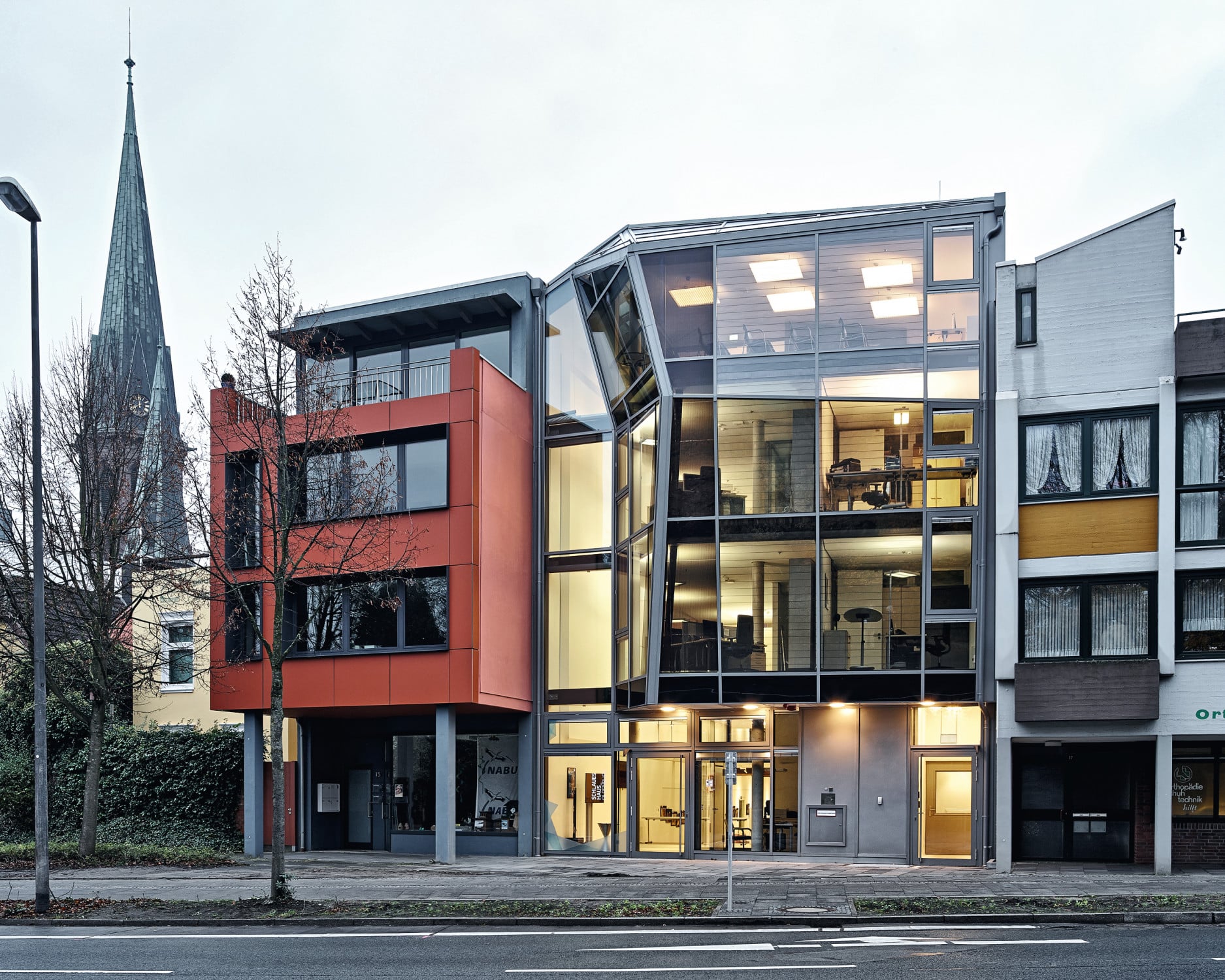 Die „Rückseite“ zum Schlossgarten hin mit dem gläseren Erweiterungsbau zwischen den Nachbargebäuden mit roter Eternit- und Sichtbetonfassade
