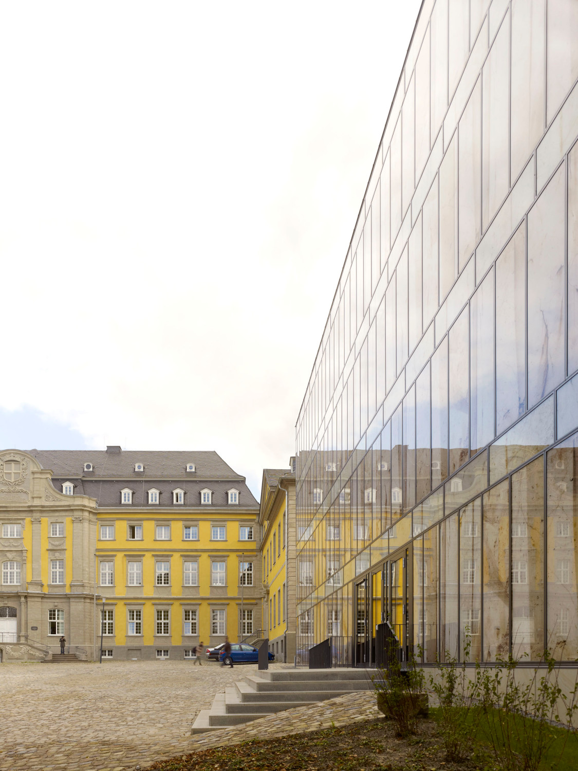 Der Neubau erscheint wie eine spiegelnde Natursteinfassade