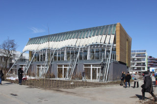 Die Südfassade ist großflächig verglast; die Obergeschosse werden von einer dynamischen Fassade aus Membran-Lamellen verschattet