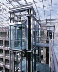 Gemäß Bauregelliste sind Fahrschachttüren geregelte Bauprodukte (Abb.: Glasaufzug im Atrium Friedrichstraße in Berlin von gmp Architekten).