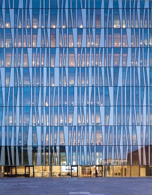 Bei Dunkelheit scheint das Innenleben durch die Vorhangfassade aus Glas und die gedämmten Aluminiumpaneele