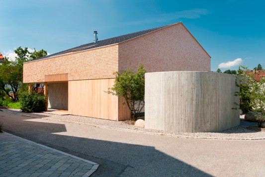 Blick auf die zweigeteilte Westfassade mit Fahrradabstellraum aus Sichtbeton
