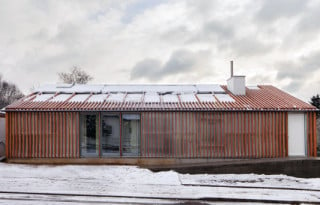 Von Westen her zeigt sich das komplett eingehüllte Wohnhaus als eingeschossiges Gebäude