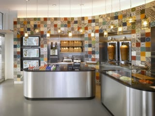 Die gebogene Rückwand mit farbenfrohem Fliesen-Patchwork prägt die Atmosphäre des kleinen Dönerladens